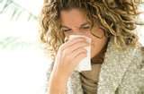 Woman sneezing into tissue